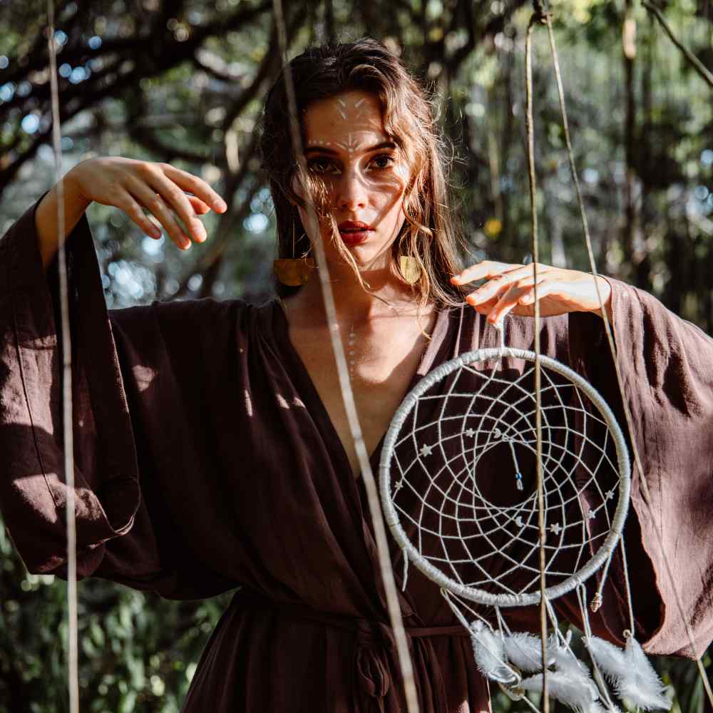 a woman holding a white dream catcher