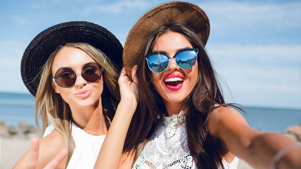 duas mulheres com óculos de sol na praia